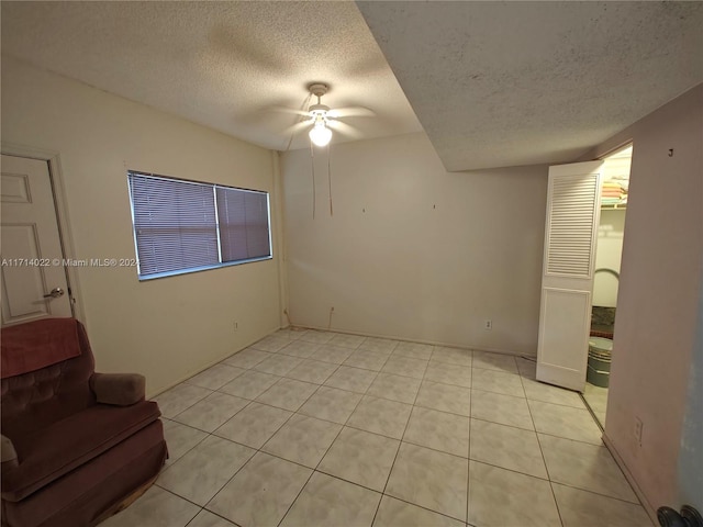 living room featuring light tile patterned floors, a textured ceiling, and ceiling fan