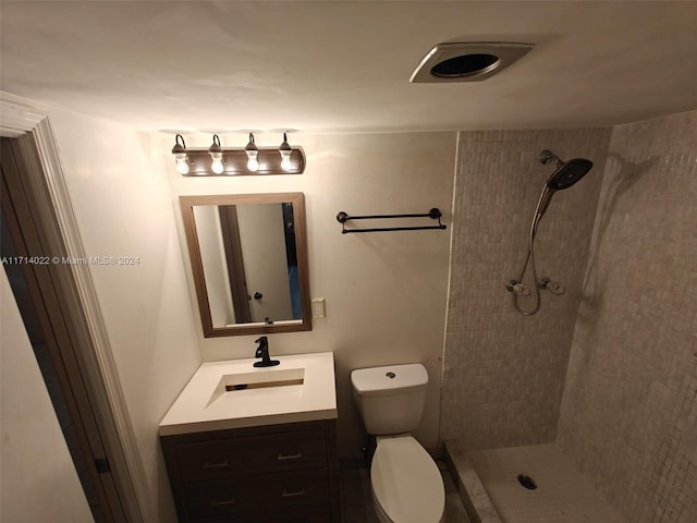 bathroom featuring vanity, toilet, and tiled shower