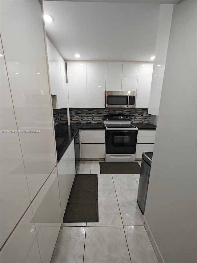 kitchen with white cabinets, decorative backsplash, light tile patterned floors, and white electric stove