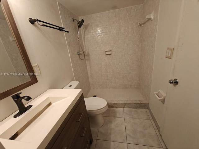 bathroom featuring a tile shower, tile patterned flooring, vanity, and toilet