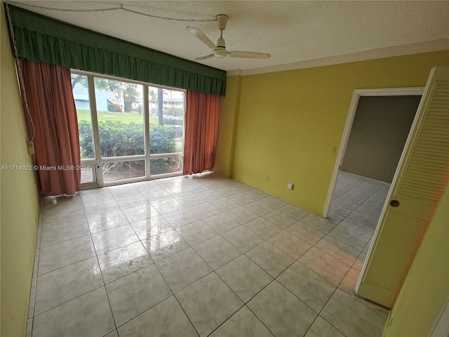 tiled empty room with ceiling fan and a textured ceiling