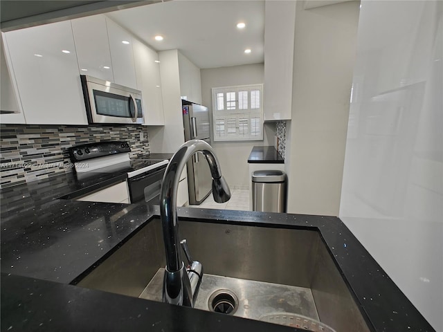 kitchen with white cabinets, decorative backsplash, sink, and stainless steel appliances