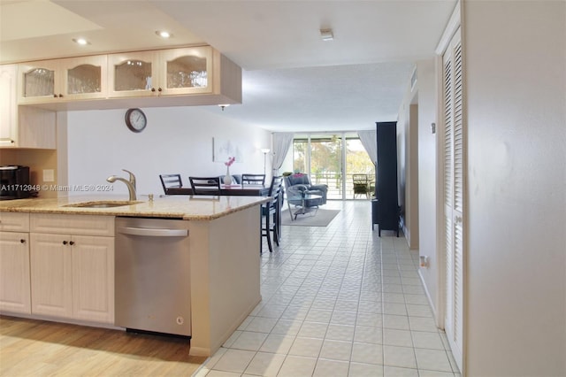 kitchen with light stone counters, stainless steel dishwasher, expansive windows, sink, and light tile patterned flooring