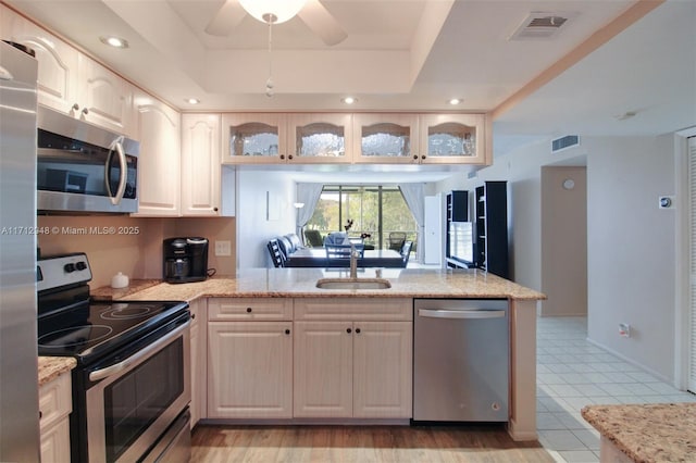 kitchen featuring appliances with stainless steel finishes, a ceiling fan, a sink, glass insert cabinets, and recessed lighting