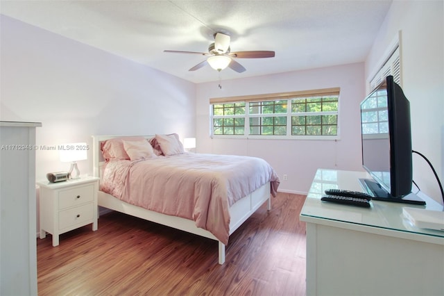 bedroom with wood finished floors, a ceiling fan, and baseboards