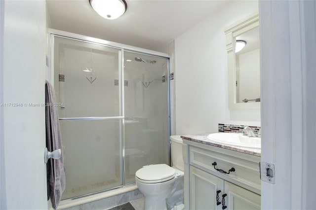 bathroom with vanity, tasteful backsplash, toilet, and an enclosed shower