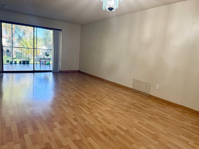 empty room with visible vents, baseboards, a textured ceiling, and light wood-style flooring