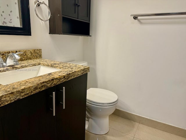 half bath with tile patterned flooring, toilet, vanity, and baseboards