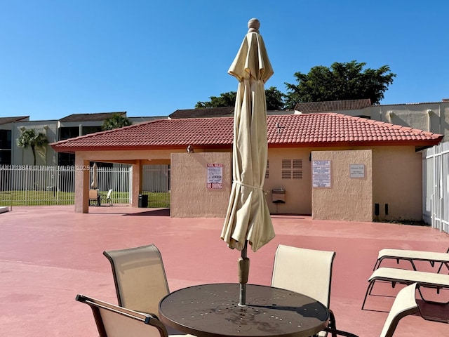 exterior space featuring stucco siding, outdoor dining space, a tile roof, fence, and a patio area