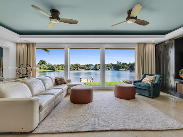 living room with plenty of natural light, ceiling fan, a water view, and a tray ceiling