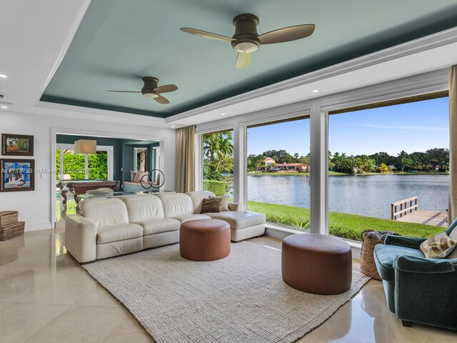 living room with a tray ceiling, ceiling fan, and a water view