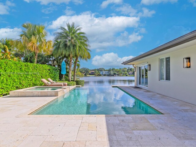 view of swimming pool featuring a water view, an in ground hot tub, and a patio