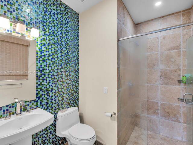 bathroom featuring sink, decorative backsplash, toilet, tile walls, and walk in shower