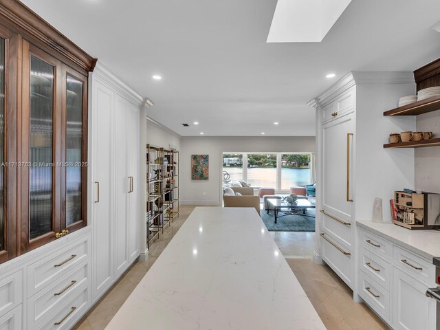 kitchen featuring light stone countertops, light tile patterned floors, and white cabinets