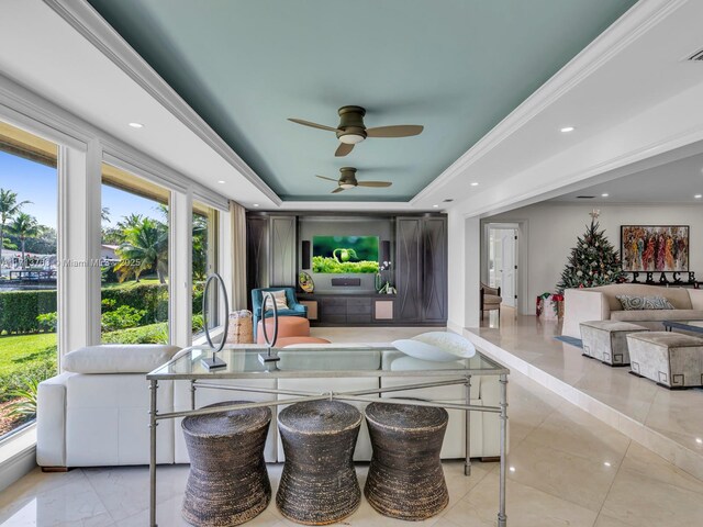 living room with ceiling fan, a raised ceiling, and crown molding