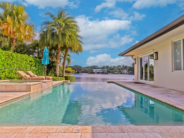 view of swimming pool featuring an in ground hot tub, a patio, and a water view