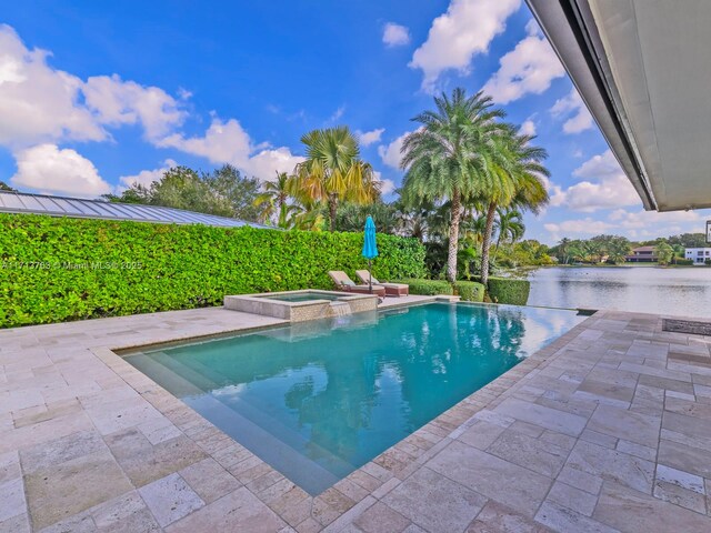 view of swimming pool with an in ground hot tub, a water view, and a patio