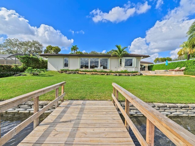 back of house featuring a deck with water view and a lawn