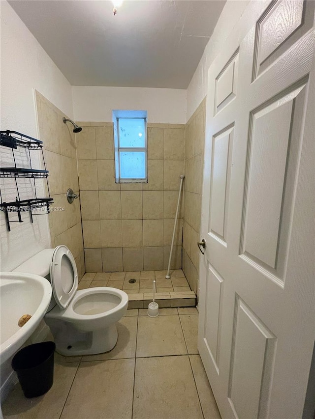 bathroom with tile patterned floors, sink, toilet, and tiled shower