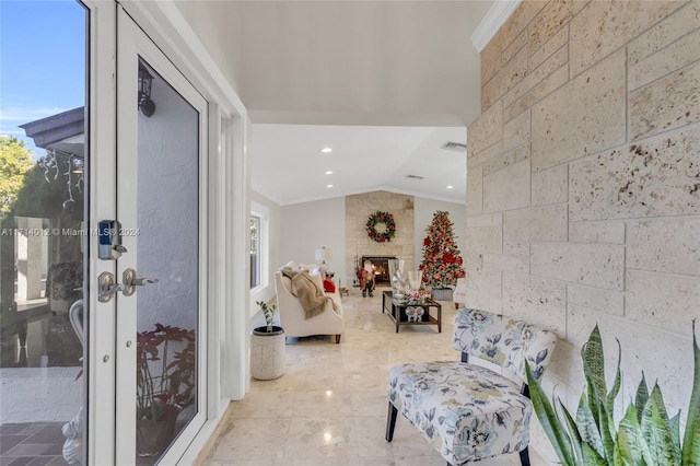 interior space with lofted ceiling, a fireplace, crown molding, and visible vents