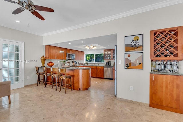 kitchen featuring brown cabinetry, appliances with stainless steel finishes, a peninsula, crown molding, and a kitchen bar