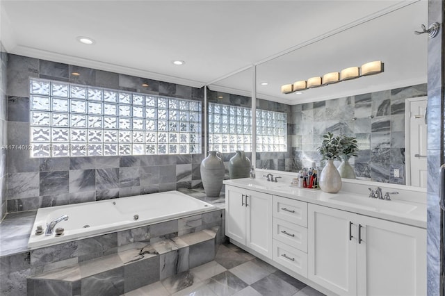 full bathroom featuring double vanity, a jetted tub, a sink, and tile walls