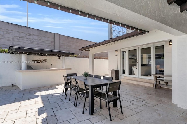 view of patio featuring outdoor dining area, exterior kitchen, and french doors