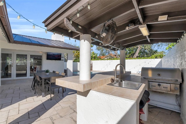 view of patio with area for grilling, a fenced backyard, exterior kitchen, french doors, and a sink