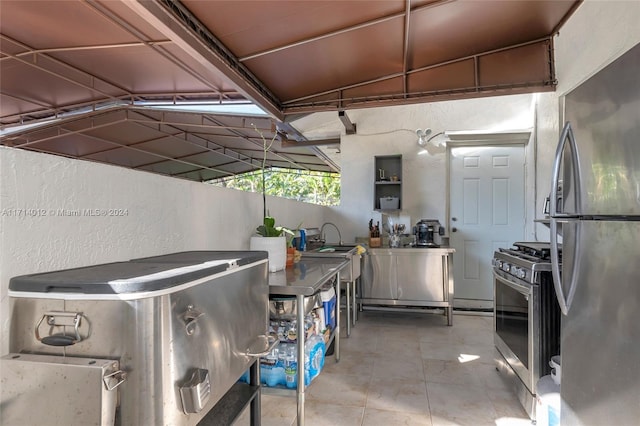 kitchen with tile patterned flooring, stainless steel appliances, a sink, and a textured wall