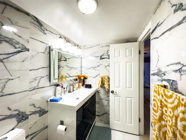 bathroom featuring vanity, toilet, and tile walls