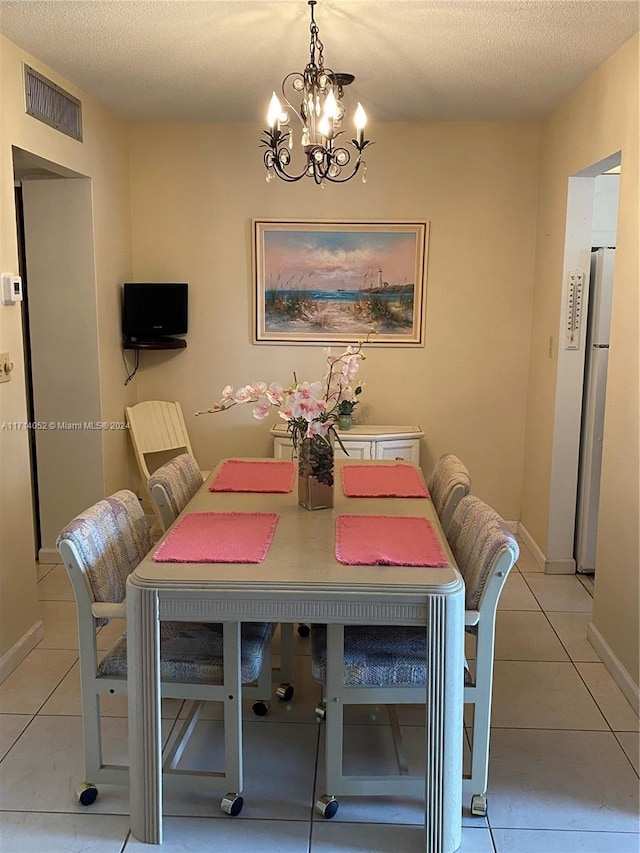 dining space with light tile patterned floors, a chandelier, and a textured ceiling