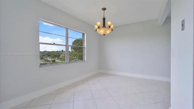 spare room with beamed ceiling, light tile patterned floors, and a chandelier