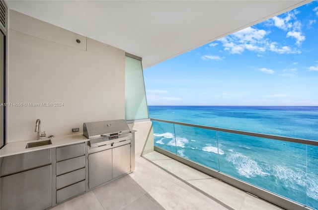 balcony with grilling area, sink, a water view, and exterior kitchen