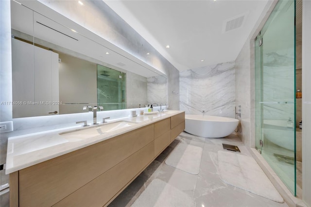 bathroom featuring vanity, independent shower and bath, and tile walls