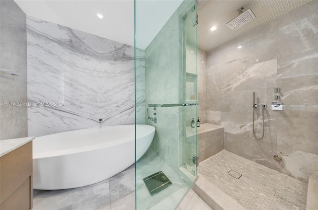 bathroom featuring plus walk in shower, vanity, and tile walls