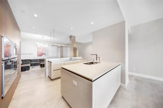 kitchen featuring pendant lighting, stovetop, sink, and an island with sink