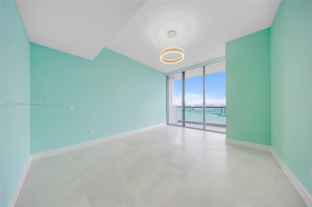 unfurnished room with a water view and a wall of windows