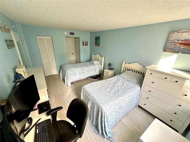 bedroom featuring light hardwood / wood-style flooring, a textured ceiling, and a closet