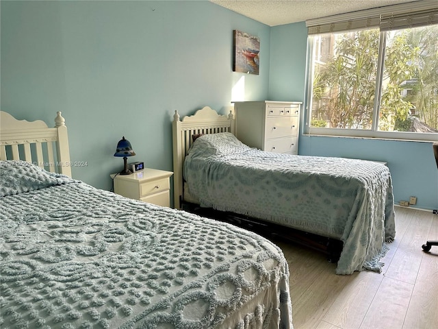 bedroom featuring a textured ceiling and light hardwood / wood-style flooring