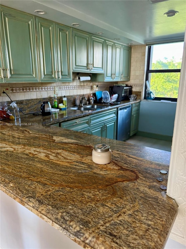 kitchen with sink, green cabinets, stainless steel dishwasher, backsplash, and dark stone counters