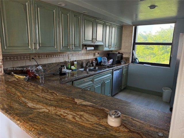 kitchen with dark stone counters, decorative backsplash, sink, and stainless steel dishwasher