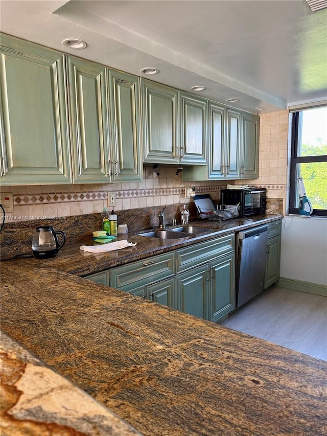 kitchen featuring green cabinets, sink, light hardwood / wood-style flooring, stainless steel dishwasher, and decorative backsplash