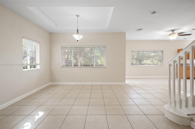 spare room featuring a raised ceiling, ceiling fan, and light tile patterned flooring