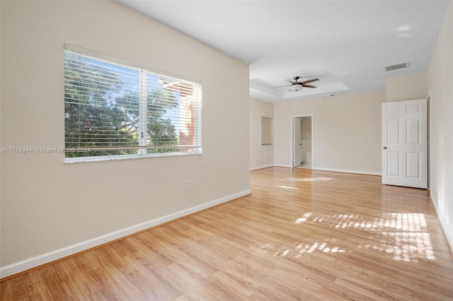 unfurnished room with light hardwood / wood-style flooring, a raised ceiling, and ceiling fan