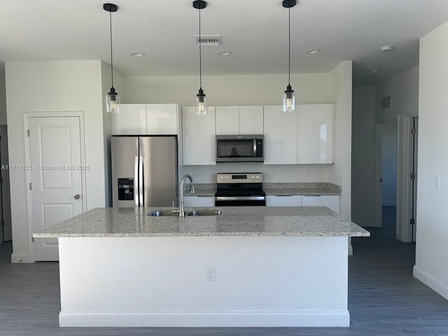 kitchen with white cabinets, stainless steel appliances, a kitchen island with sink, and sink