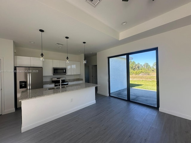 kitchen with light stone countertops, appliances with stainless steel finishes, sink, a center island with sink, and white cabinets