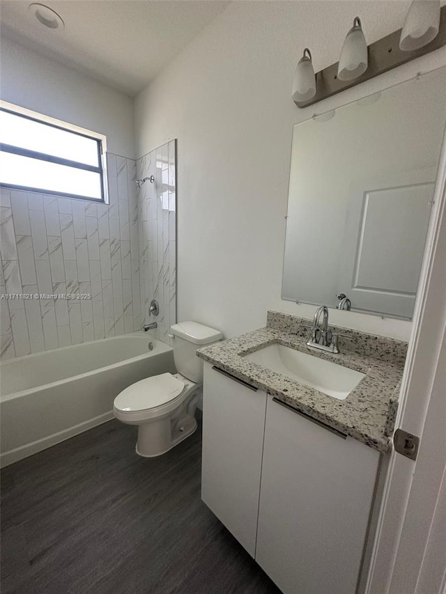 full bathroom with vanity, hardwood / wood-style floors, tiled shower / bath combo, and toilet