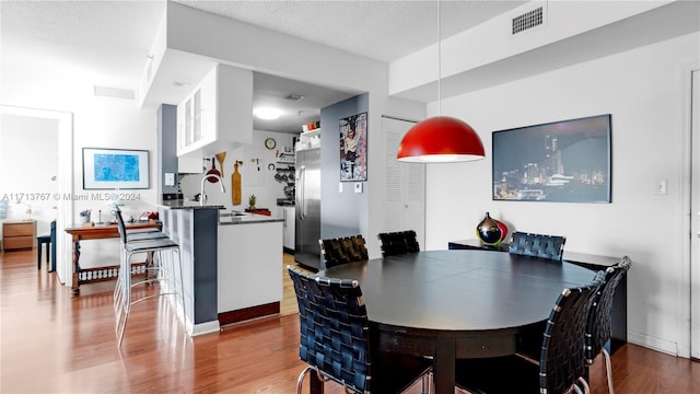 dining area with hardwood / wood-style floors, a textured ceiling, and sink