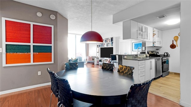 dining space with a textured ceiling, light hardwood / wood-style floors, and sink