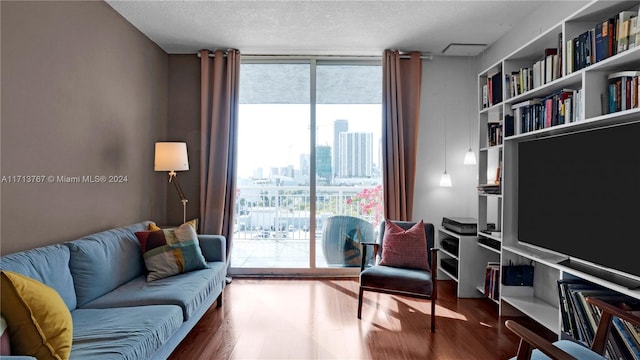 living room with built in shelves, hardwood / wood-style floors, a textured ceiling, and a wall of windows